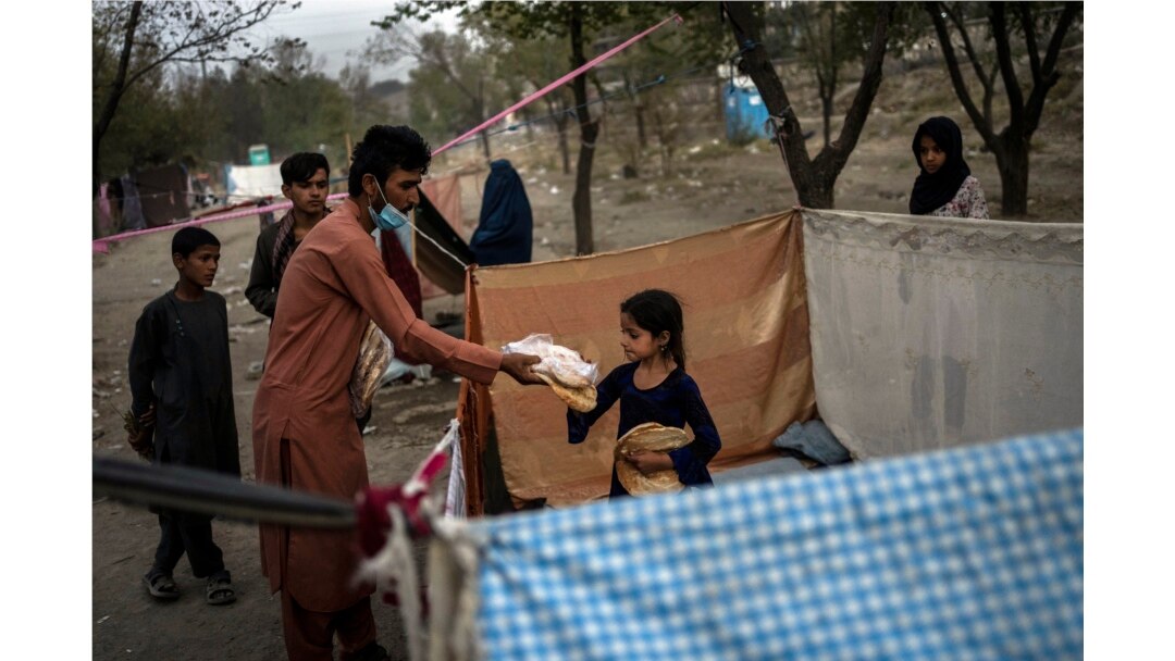 Displaced Afghans distribute food donations at an internally displaced persons camp in Kabul, Afghanistan, Sept. 13, 2021.