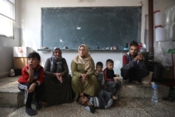 FILE - Members of a displaced Kurdish family sit at a public school they use as a temporary shelter, in Hasakah, Syria, Oct. 22, 2019.