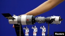 在酒泉衛星發射中心展示的中國神舟9號飛船與三名中國宇航員的模型。（2012年6月15日）