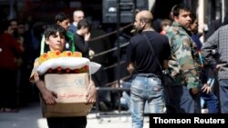 FILE - A boy holds a cardboard box of food aid in Aleppo's Kalasa district, Syria, April 10, 2019.