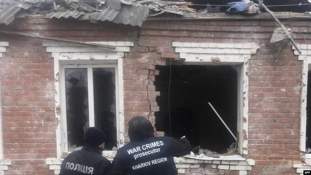 Esta fotografía tomada y publicada por la Oficina del Fiscal General de Ucrania el 6 de febrero de 2024 muestra a agentes del orden de pie junto a una casa dañada como resultado de un ataque con misiles en Zolochiv, región de Kharkiv, Ucrania.