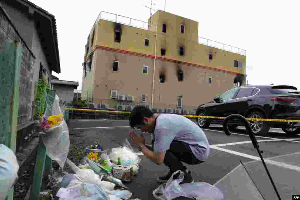 A man prays next to flowers and tributes laid at the scene where more than 33 people died and scores injured in a suspected arson attack on an animation company building in Kyoto, Japan.