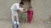 FILE - An Afghan health worker administers polio vaccine to a child during a campaign at a refugee camp on the outskirts of Jalalabad in Nangarhar province on May 11, 2015.