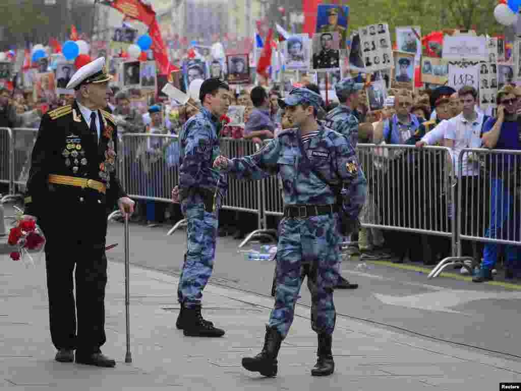 A member of Russia's National Guard presents flowers to a veteran during celebrations of Victory Day, which marks the anniversary of the victory over Nazi Germany, Moscow, May 9, 2019.