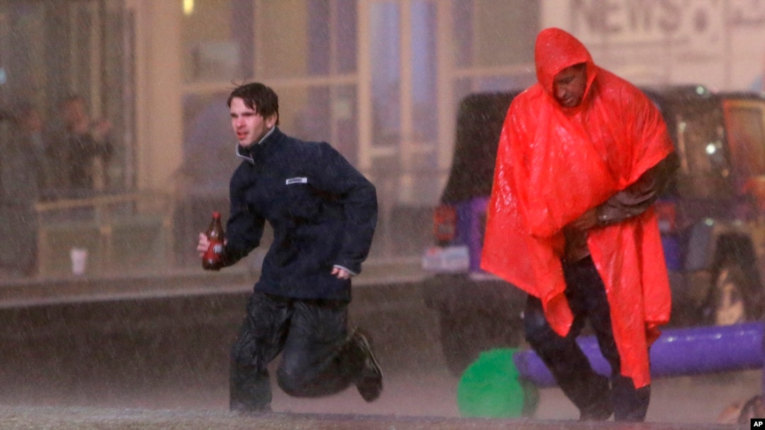 Gente busca cubrirse de una torrencial lluvia en el centro de Dallas, Texas.