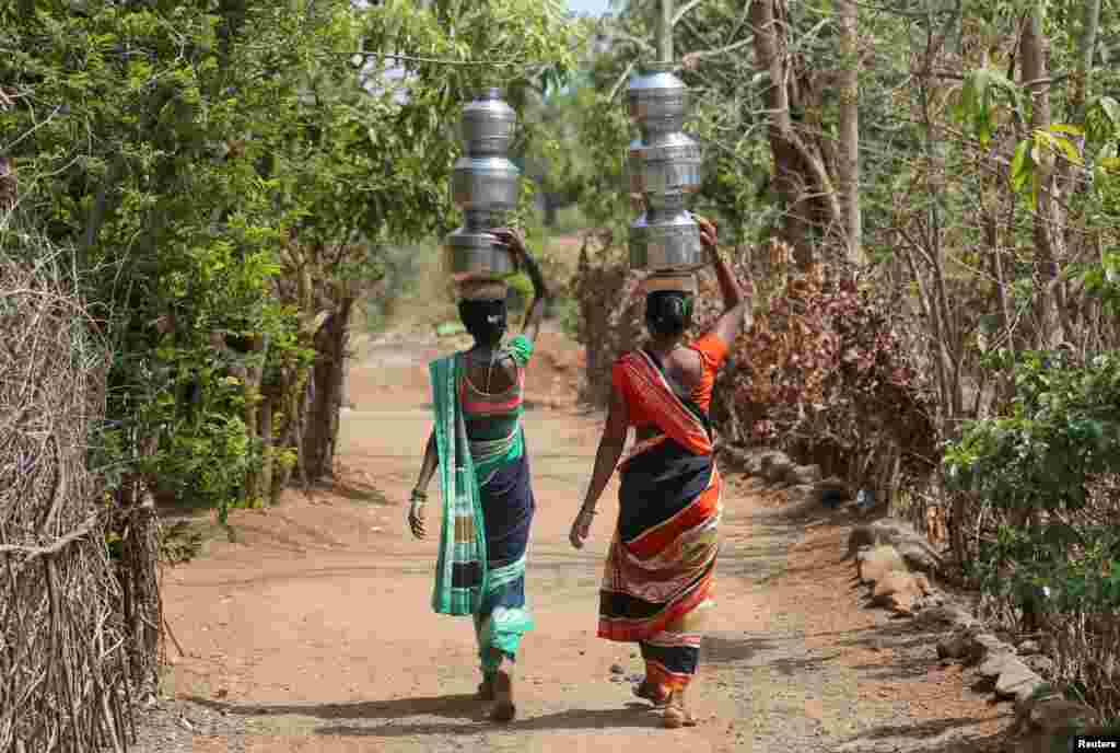 Women carry water pitchers to their houses in Thane district in the western state of Maharashtra, India.