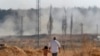 People walk in Akcakale, Sanliurfa province, southeastern Turkey, as in the background, Turkish forces artillery pieces fire targets towards Syria, Oct. 11, 2019.