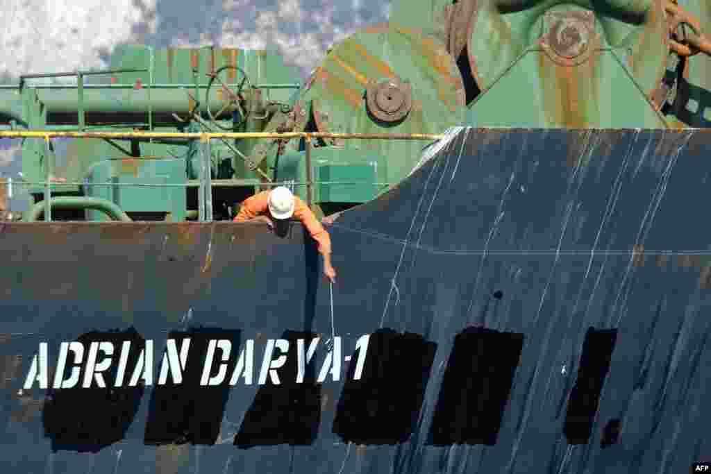 A crew member checks the new name of Iranian oil tanker Adrian Darya, formerly known as Grace 1, off the coast of Gibraltar. Gibraltar rejected a U.S. demand to seize the tanker at the center of a diplomatic dispute as it prepared to leave the British overseas territory after weeks of detention.