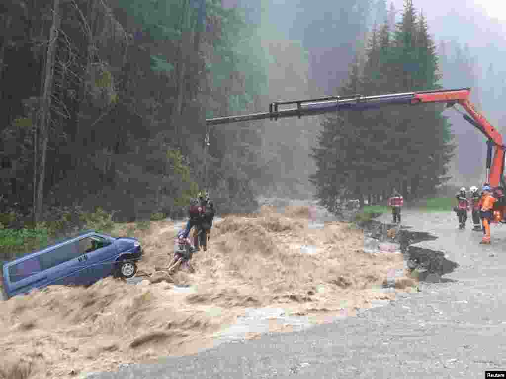 Two occupants of stranded van are lifted unhurt by a crane during heavy rain in this picture released by the Graubuenden Police in Spluegen, Switzerland, June 12, 2019.