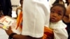 FILE - A mother carries a child on her back as she visits an exhibition on HIV/AIDS in Gaborone, Botswana. The country has reached a viral suppression rate of 96 percent among its infected citizens.