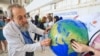Environmental activists stage a protest with a earth globe during a demonstration at the venue of the COP28 United Nations climate summit in Dubai on Dec. 6, 2023.