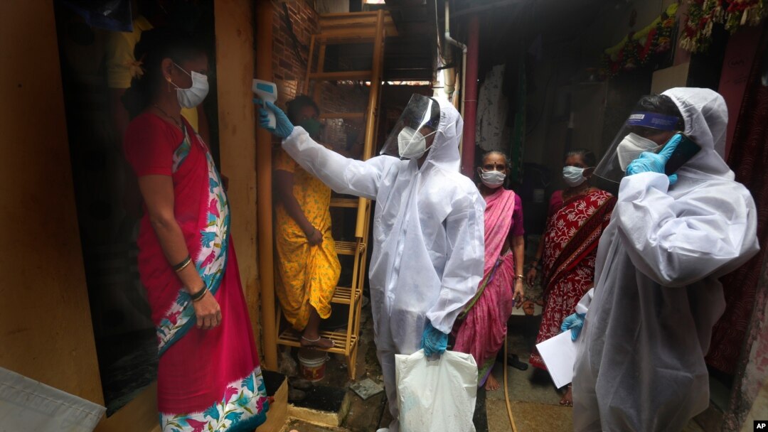 A health worker checks the body temperature of residents during a free medical checkup in a slum in Mumbai, India, the fourth hardest-hit country by the COVID-19 pandemic in the world after the U.S., Russia and Brazil, June 28, 2020.
