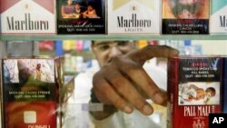 FILE - A Singaporean shopkeeper reaches to get a pack of cigarettes. Lawmakers in Singapore have passed tighter restrictions on tobacco sales aimed at reducing smoking rates.