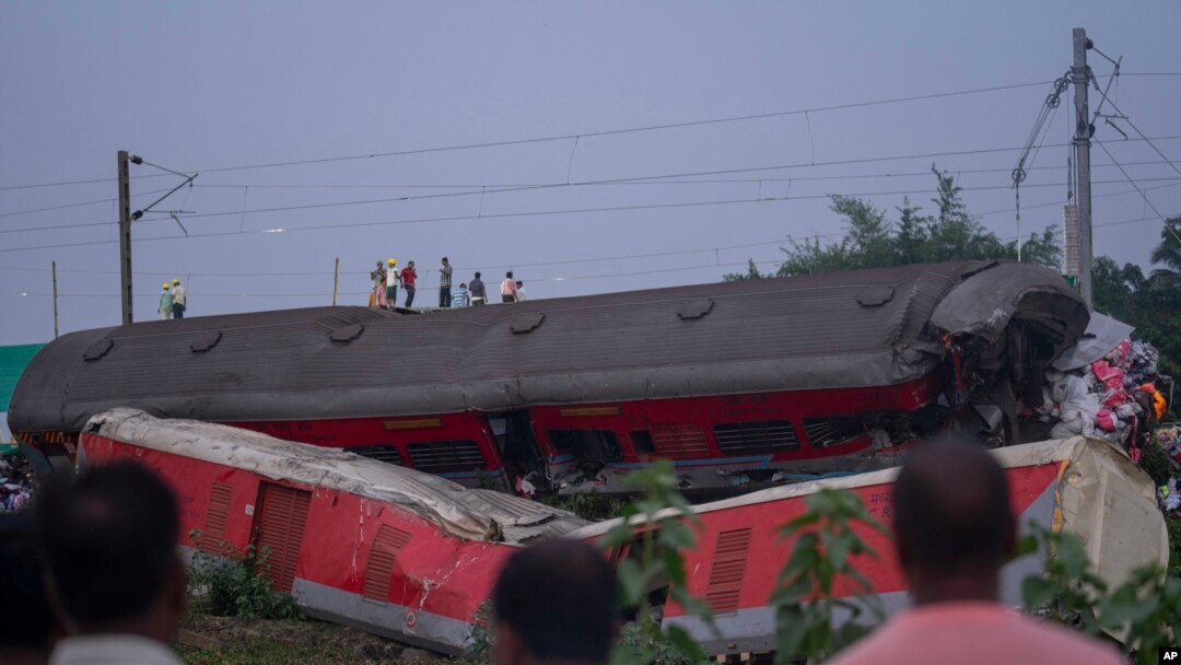La gente mira los restos destrozados de los dos trenes de pasajeros que descarrilaron el viernes en el distrito de Balasore, en el estado oriental de Orissa, India, el domingo 4 de junio de 2023.