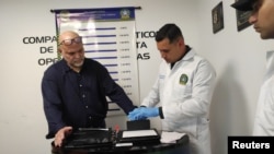 Un policía toma huellas dactilares al ex comandante de las Autodefensas Unidas de Colombia (AUC), Salvatore Mancuso, luego de llegar a Colombia extraditado de Estados Unidos al Comando Aéreo de Transporte Militar (CATAM) en Bogotá, Colombia, el 27 de febrero de 2024.