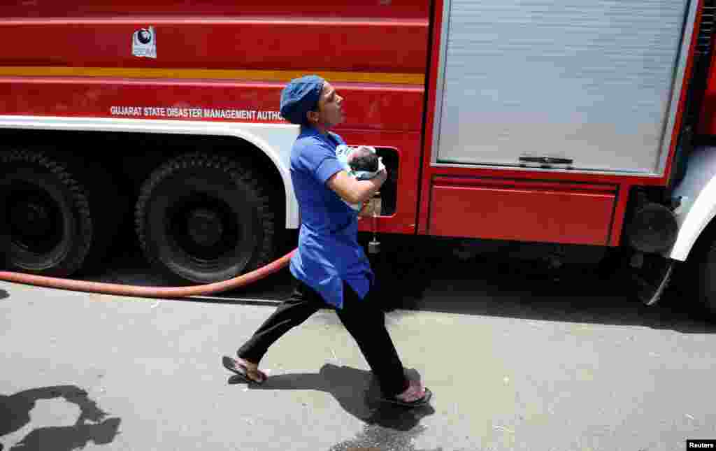 A nurse carries a newborn baby after a fire broke out on the terrace of a children's hospital building in Ahmedabad, India.
