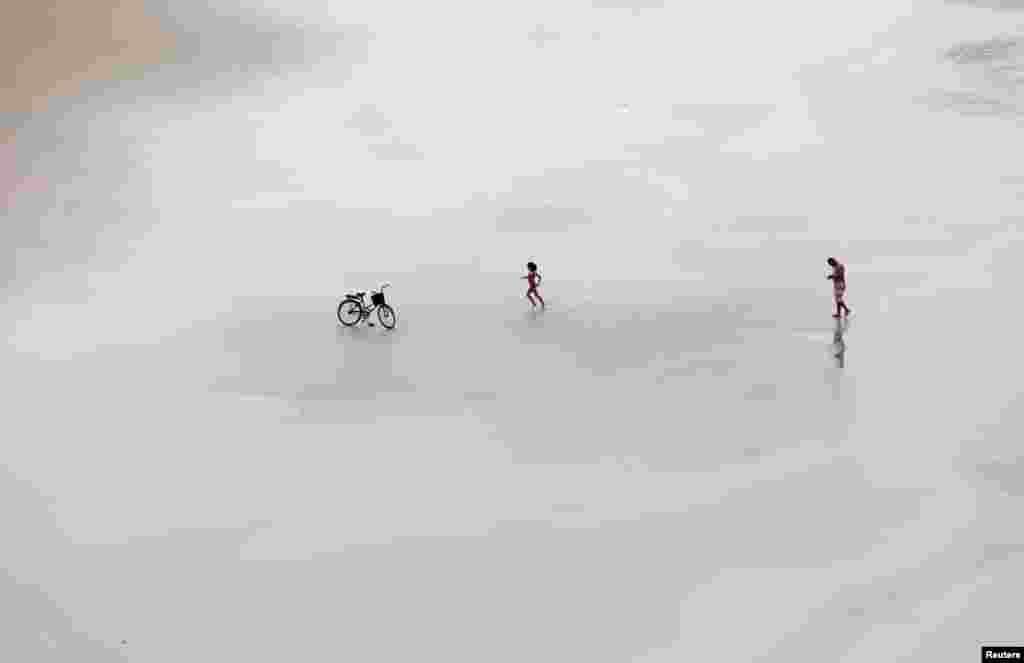 A girl runs towards her bicycle on a beach in Guaruja, Sao Paulo state, Brazil, June 18, 2019.