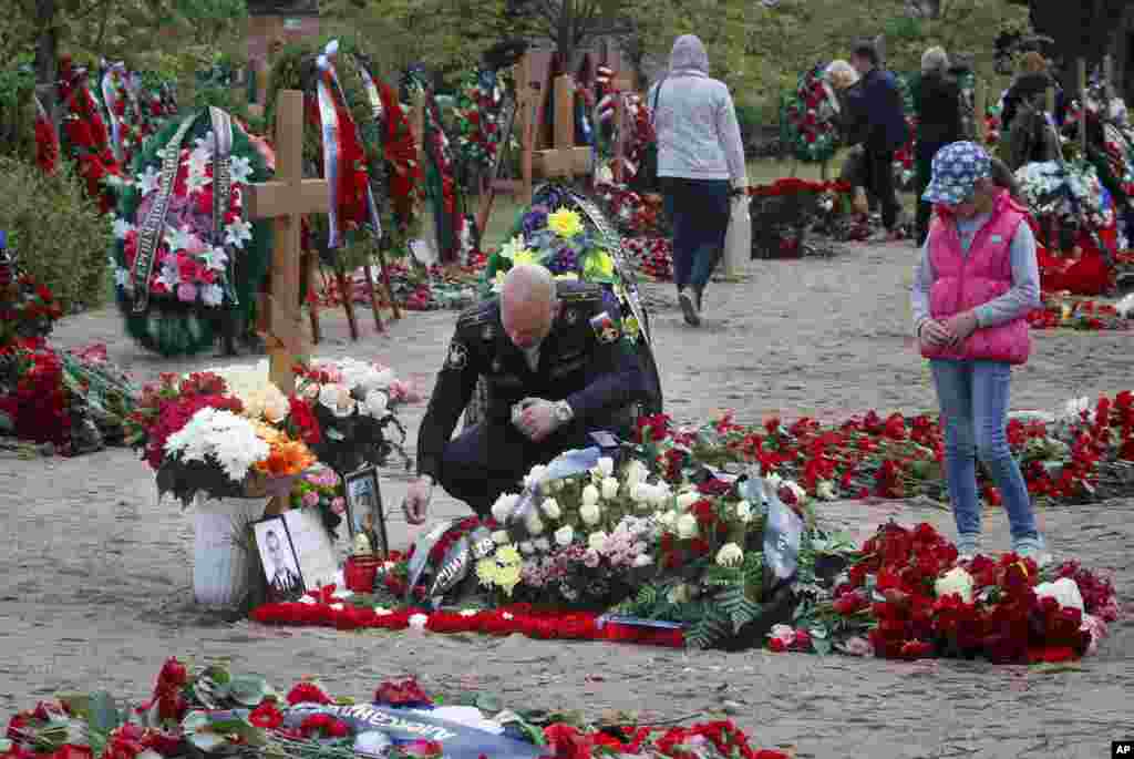 A Russian navy officer lights a candle as he pays his last respect at the grave of Captain 3rd rank Vladimir Sukhinichev, one of the 14 crew members who died in a fire on a Russian navy's deep-sea research submersible, at the Serafimovskoye memorial cemetery during a funeral ceremony in St. Petersburg, July 6, 2019. President Vladimir Putin awarded the nation's highest honors to 14 seamen who died in a fire on one of the navy's research submersibles.