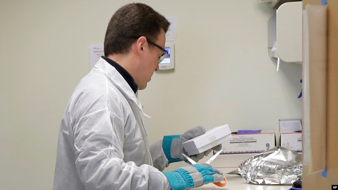 A pharmacist in Seattle opens a package taken from a freezer that contains a potential vaccine for COVID-19, on the first day of a first-stage safety study clinical trial of the vaccine, March 16, 2020.