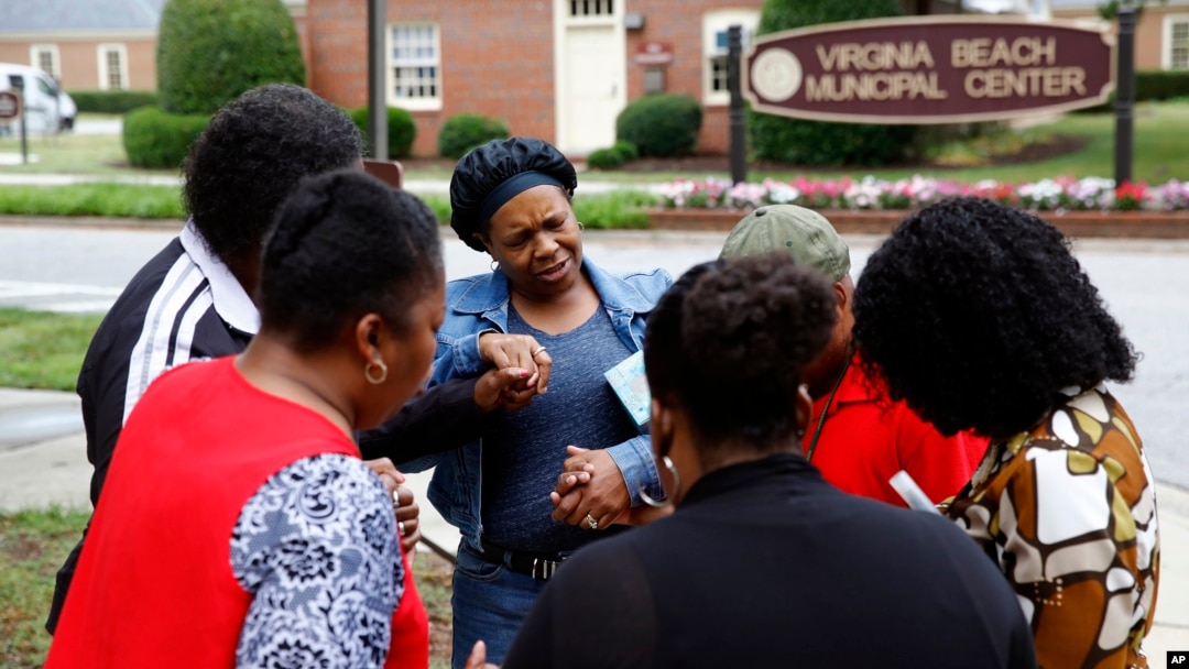 Members of Mount Olive Baptist Church pray near a municipal building that was the scene of a shooting, June 1, 2019, in Virginia Beach, Va. (AP Photo/Patrick Semansky)