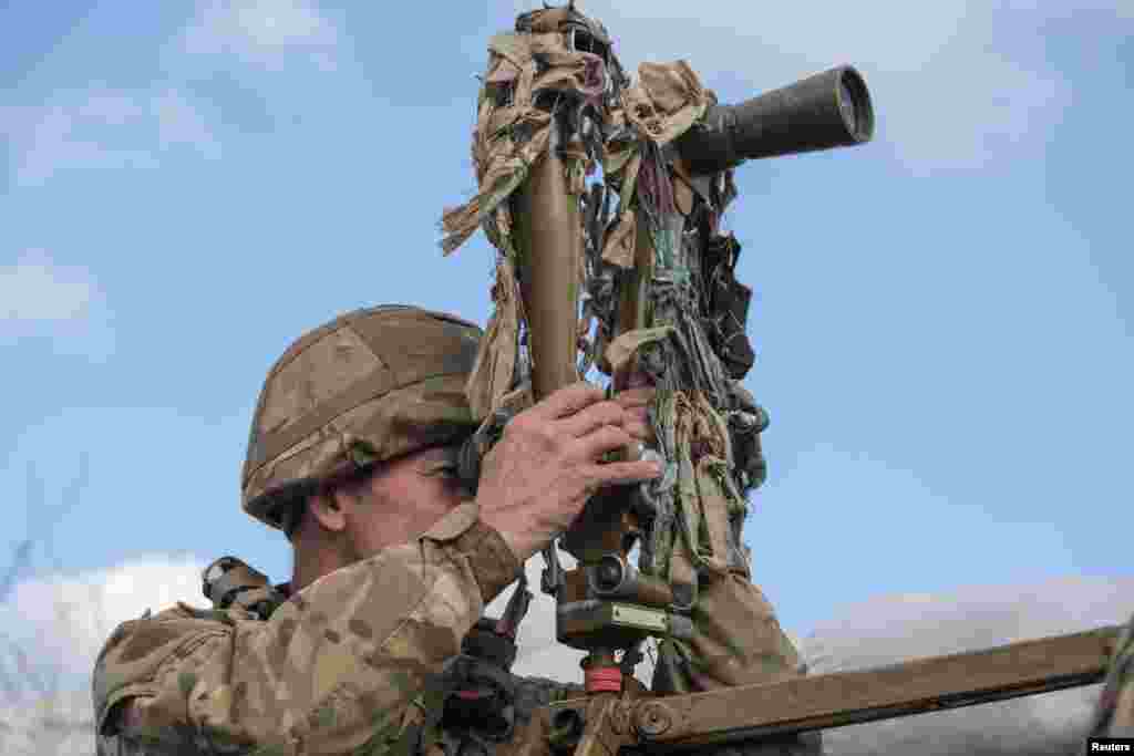 A service member of the Ukrainian armed forces uses periscopes while observing the area at fighting positions on the line of separation near the rebel-controlled city of Donetsk, Ukraine.