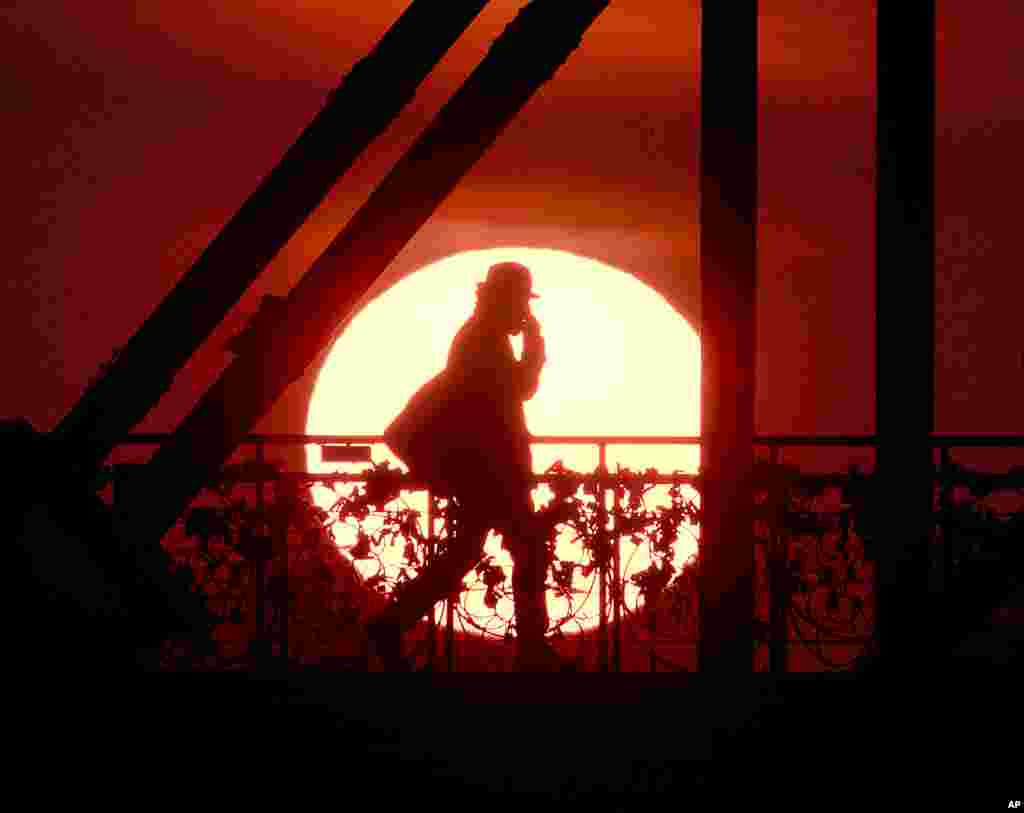The sun rises behind the 'Eiserne Steg' (Iron Footbridge) pedestrian bridge in Frankfurt, Germany.