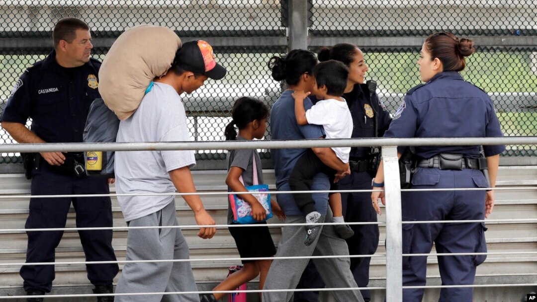 FILE - In this June 21, 2018, photo, Ever Castillo, left, and his family, immigrants from Honduras, are escorted back across the border by US Customs and Border Patrol agents in Hildalgo, Texas. 
