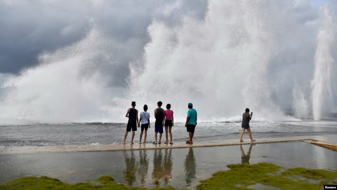 ARCHIVO - Un grupo de cubanos observa las olas que se estrellan contra el Malecón de La Habana mientras el huracán Milton pasa cerca de la costa cubana, el 9 de octubre de 2024. Muchos cubanos se lanzan al mar para intentar llegar a EEUU en peligrosos viajes.