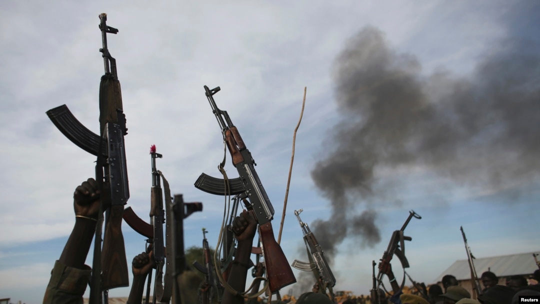 Rebel fighters hold up their rifles as they walk in front of a bushfire in a rebel controlled territory in Upper Nile State, South Sudan, Feb. 13, 2014. 