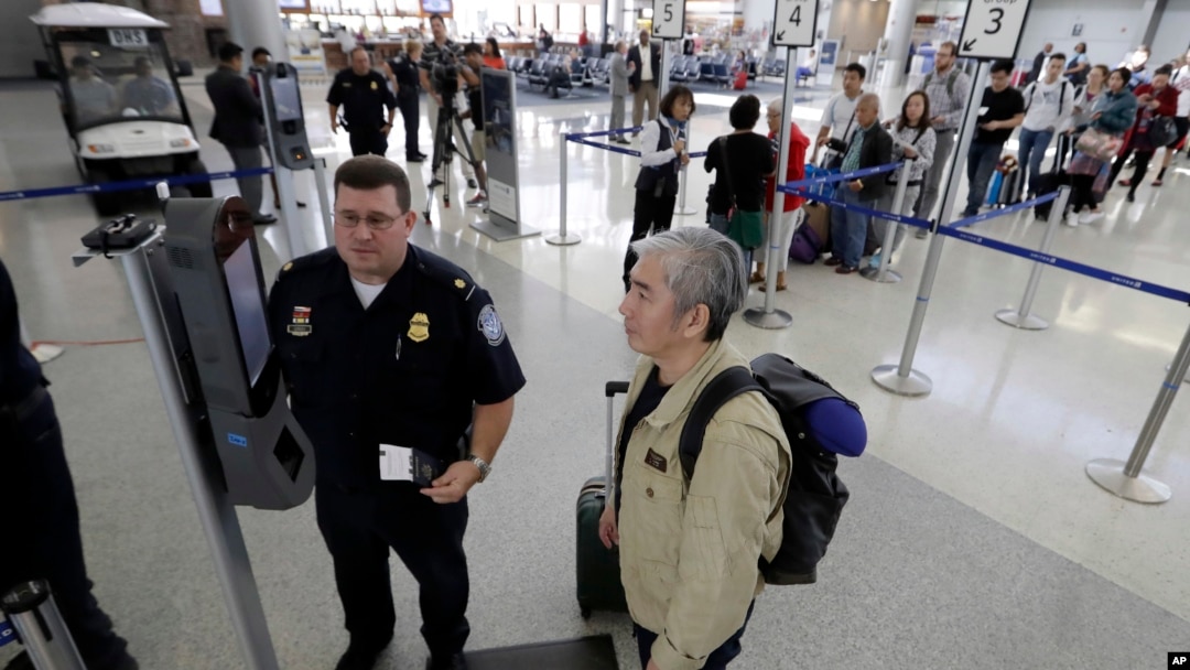 U.S. Customs and Border Protection supervisor Erik Gordon, left, helps a passenger navigate one of the new facial recognition kiosks at a United Airlines gate before boarding a flight to Tokyo, Wednesday, July 12, 2017, at George Bush Intercontinental Air