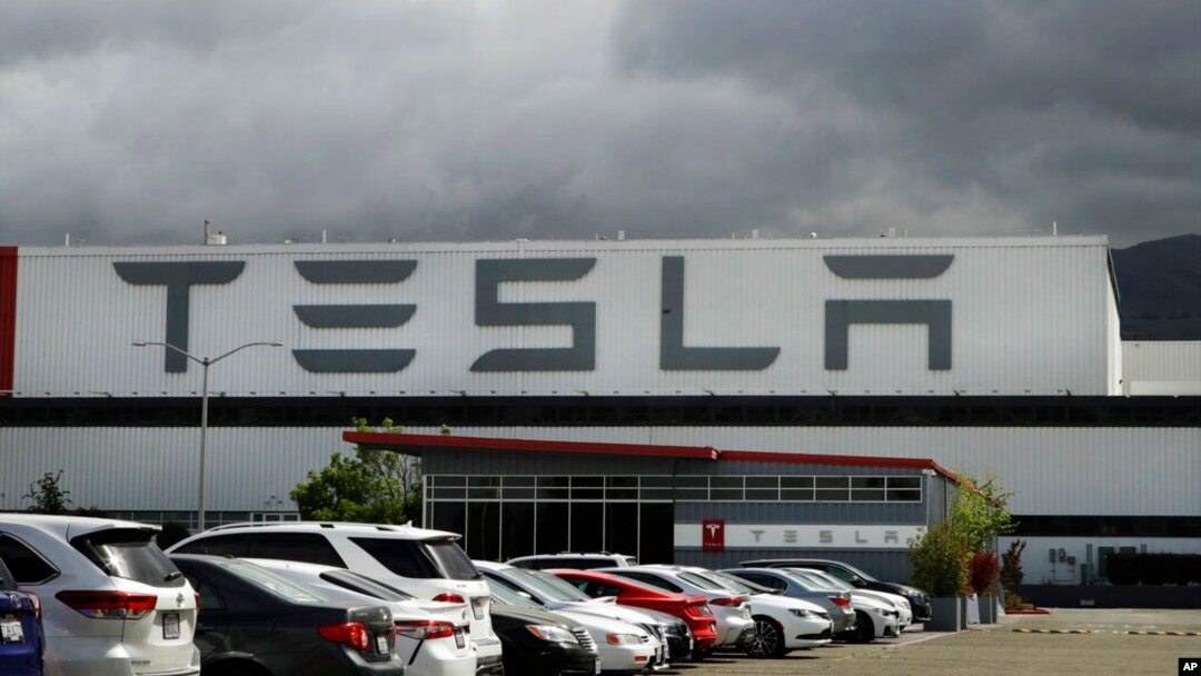 FILE - Vehicles are parked outside the Tesla plant, in Fremont, Calif., May 12, 2020. 