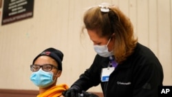 FILE - A woman receives a dose of the Pfizer COVID-19 vaccine in Wilmington, Calif., April 13, 2021. 