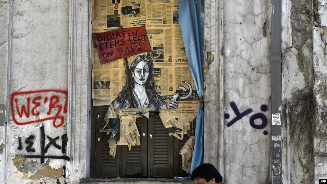 A man walks past a political graffiti in central Athens by artist Bleeps reading' Bid! a few items left on sale', May 4, 2017, one day after Greece and its creditors closed a troubled chapter on fiscal reforms.