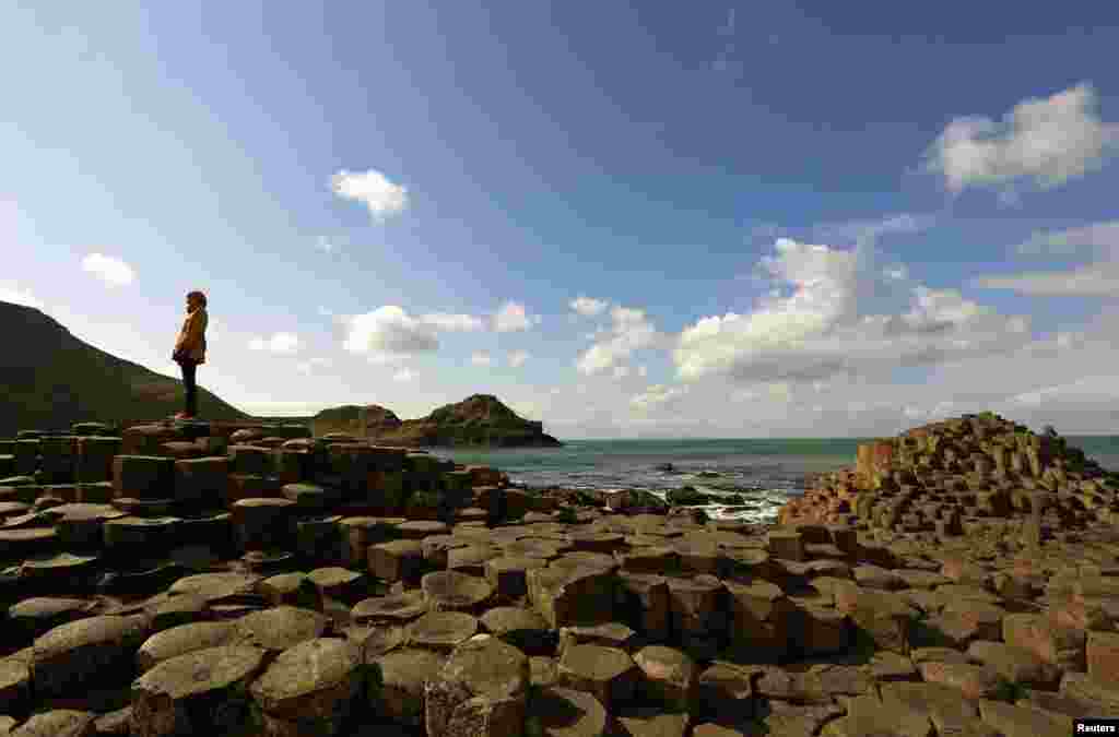 A woman stands on the rocks at the Giant's Causeway situated on the north coast of Northern Ireland.