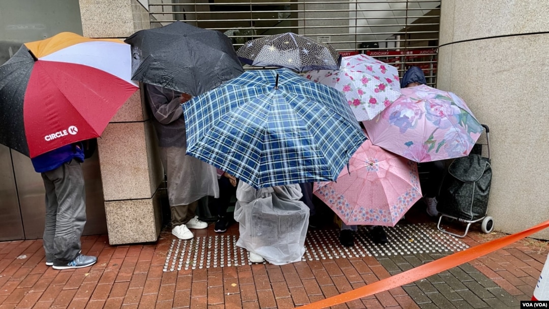 大批懷疑排隊黨今年11月中,提前3日冒雨在西九龍裁判法院外輪候民主派初選案及黎智英國安案的旁聽席,部分人用雨傘遮檔傳媒的鏡頭。(美國之音)