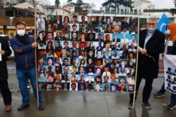 FILE - Members of the Uyghur community living in Turkey hold a placard with pictures of Uyghurs they say they fear are being kept in detention camps in China, during a protest near China's consulate in Istanbul, Feb. 10, 2021.
