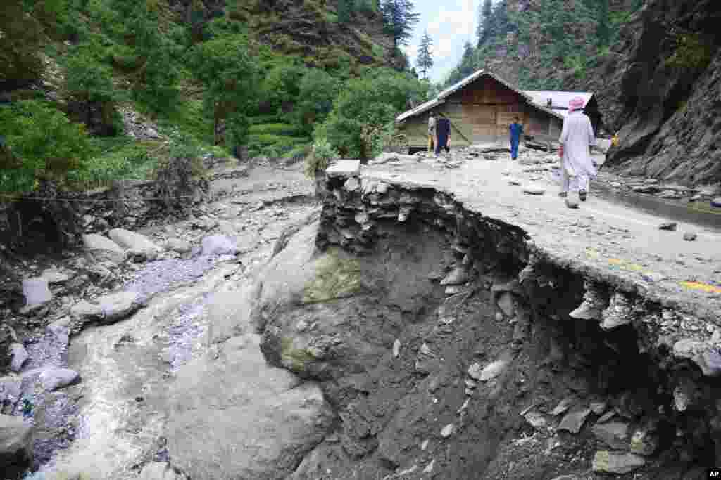 Villagers walk along a road washed away by heavy flooding in Neelum Valley of Pakistani controlled Kashmir.