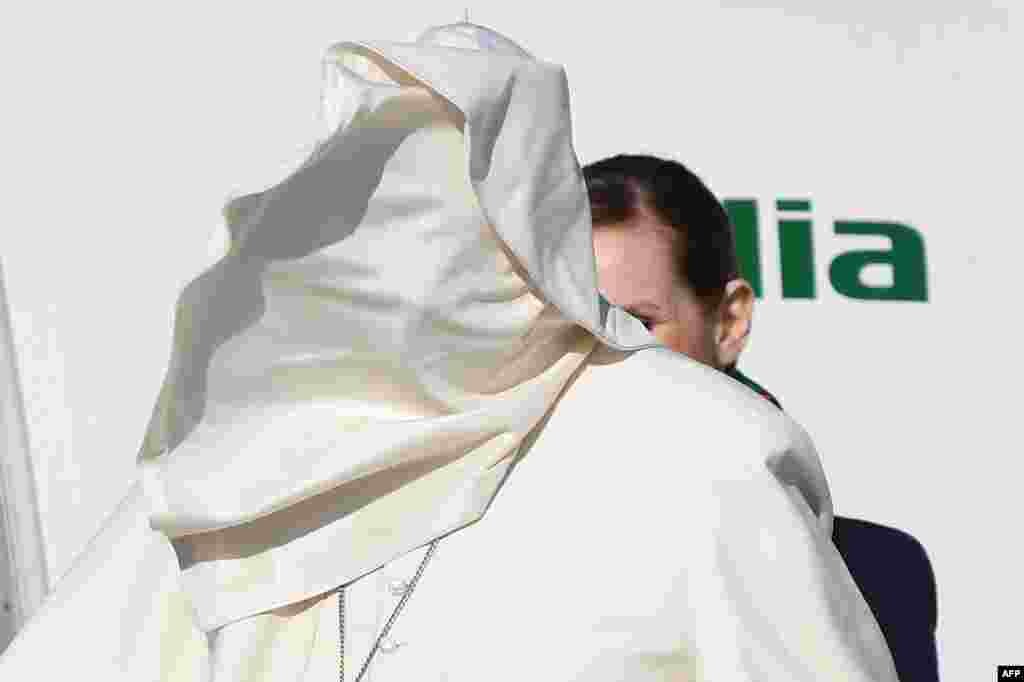 A gale of wind lifts Pope Francis' cassock upon his face as he boards a plane upon his departure for a three-day trip to Romania at Rome's Fiumicino airport, Italy.