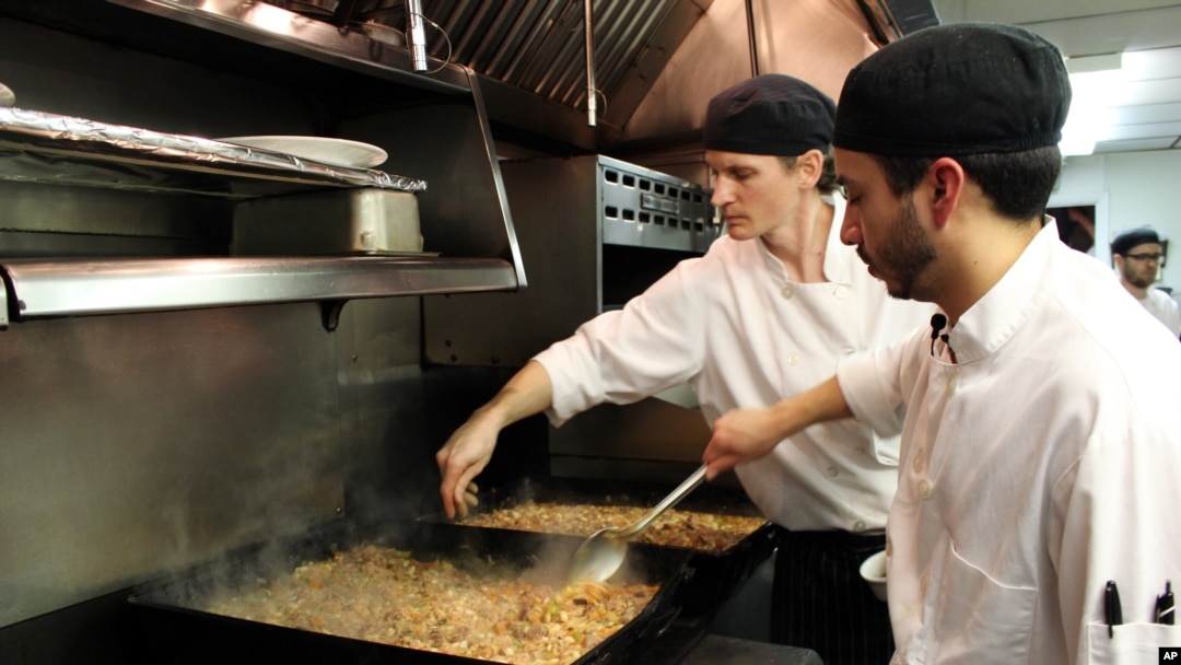 Sous chefs Adan Franco, right, and Casey Davison of the Sanford Restaurant season and stir cassoulet, to be delivered to the Guest House homeless shelter in Milwaukee, Dec. 8, 2015.