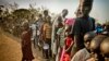 FILE - South Sudanese refugees wait in line to get food at Dzaipi transit camp in northern Uganda.