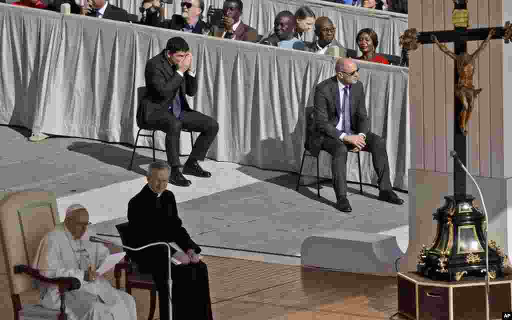 Swedish teenage environmental activist Greta Thunberg, center top, tries to get to her seat as Pope Francis delivers his message during his weekly general audience in St. Peter's Square, at the Vatican.