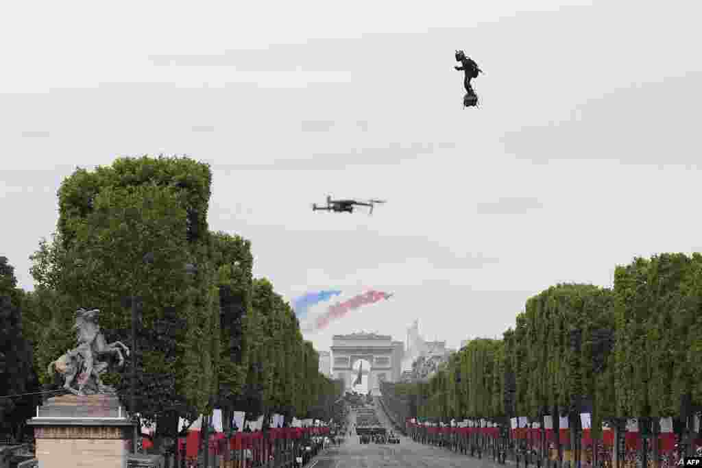 Zapata CEO Franky Zapata flies a jet-powered hoverboard or "Flyboard" as French elite acrobatic flying team "Patrouille de France" (PAF) flies over the Arc de Triomphe during the Bastille Day military parade down the Champs-Elysees avenue in Paris.