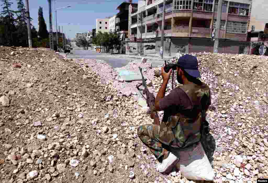 A Free Syrian Army fighter observes the area with a pair of binoculars in Aleppo, August 13, 2012.