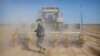 A worker walks behind a tractor during the planting of a cotton field, as seen during a government organized trip for foreign journalists, near Urumqi on April 21, 2021. Mark Schiefelbein/AP