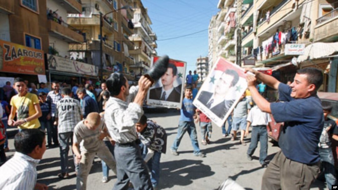 A protester uses a shoe to beat a picture of Syria's President Bashar al-Assad during a protest organized by Lebanese and Syrians living in Lebanon, in solidarity with Syria's anti-government protesters, in the port-city of Tripoli, northern Lebanon, Octo
