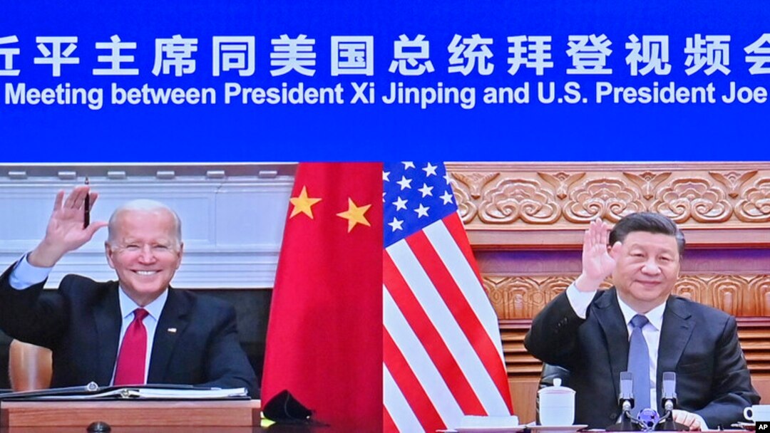 In this photo released by Xinhua News Agency, Chinese President Xi Jinping, right, and U.S. President Joe Biden appear on a screen as they hold a meeting via video link, in Beijing, China, Nov. 16, 2021. 