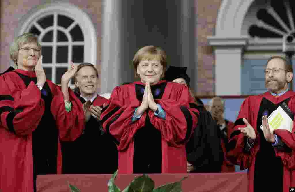 German Chancellor Angela Merkel, center, acknowledges the applause as she receives an honorary Doctor of Laws degree as former Harvard President Drew Faust, left, and Harvard Provost Alan Garber, right, look on during Harvard University Commencement Exercises in Cambridge, Massachusetts.