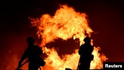 Firefighters battle a blaze, as a wind-driven wildfire continues to burn in Canyon Country north of Los Angeles, California, Oct. 25, 2019.