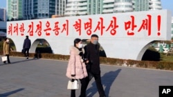 지난달 25일 북한 평양 류경체육관 인근에 적힌 김정은 국무위원장 찬양 구호 앞에서 시민들이 이동하고 있다.