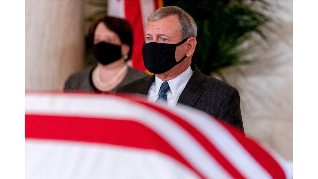 Chief Justice of the US Supreme Court, John Roberts (R) and Justice Elena Kagan (L), watch as the flag-draped casket of Justice Ruth Bader Ginsburg arrives at the Supreme Court in Washington, DC, on Sept. 23, 2020.